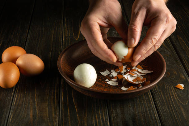 istock Preparing a delicious breakfast with boiled eggs on the kitchen table. Peeling an egg from the shell by a man hands. Egg diet concept 1922035498