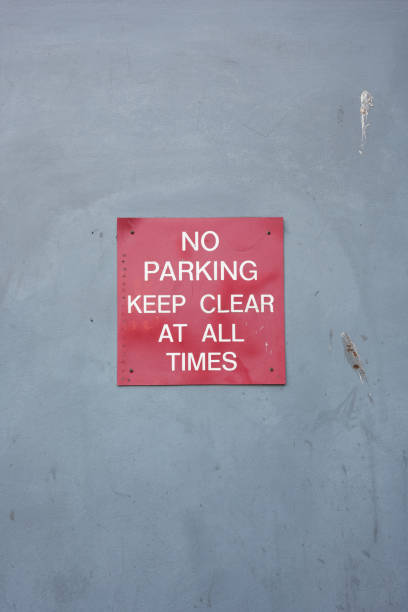 Red no parking, keep clear at all times sign on an old wall.