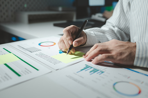 Auditor is working on accounting in the office, Businessman calculating the financial liquidity of the company, He was jotting down numbers from the company's financial documents.