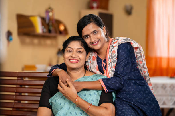 happy smiling Mother with daughter looking at camera by embracing or hugging each other at home - concept of family support, companion and emotional bonding. happy smiling Mother with daughter looking at camera by embracing or hugging each other at home - concept of family support, companion and emotional bonding indian wedding stock pictures, royalty-free photos & images