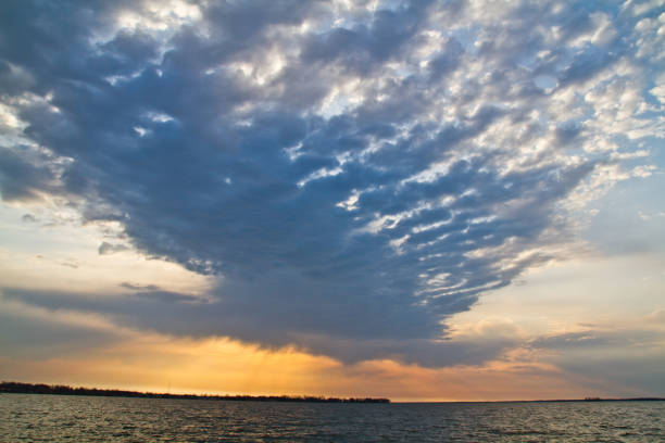 Golden Hour Serenity: Captivating view of a tranquil body of water at sunrise or sunset, with a breathtaking sky filled with billowing clouds and warm hues. Perfect for nature, meditation, and inspirational themes. Location: Indiana