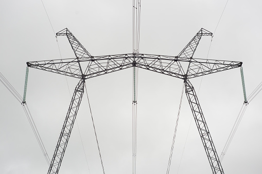 Power line support. High voltage transmission. Metal construction. Wires, insulation. Gray cloudy sky.