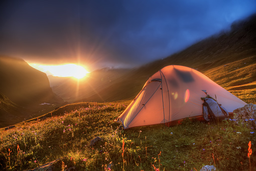 Tourist tent on the background of the evening sun. Back lighting. Selective focus in the foreground. Soft focus.