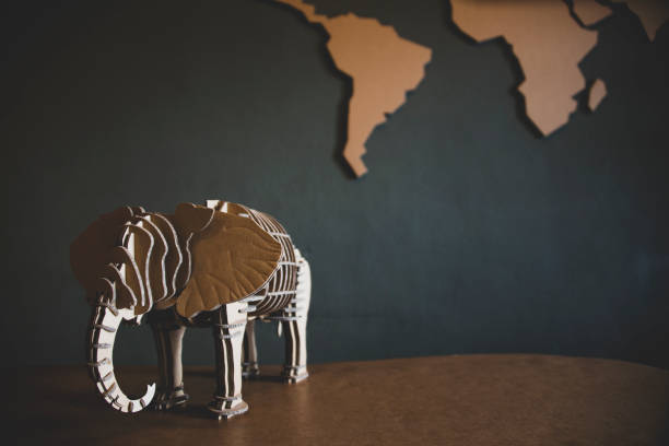 World map and elephant figurine on wooden table with blackboard background