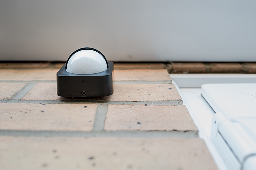 Shallow focus of a newly fitted IoT infra red sensor which is connected to automated smart lighting. Battery powered with wireless connectivity seen outside a house door.