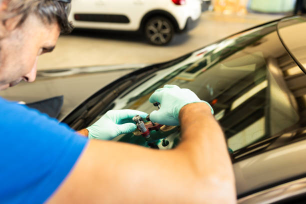 istock Automobile special workers remove old windscreen or windshield of a car in auto service station garage. Background 1922100877