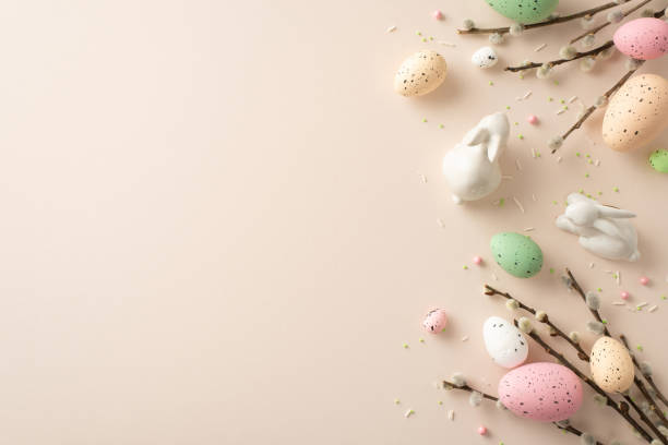 istock Experience magic of Easter with this charming setup. Top view of Easter decor, delightful ceramic bunnies, sprinkles on pastel beige background. Customize with your own text or promotional content 1922120614
