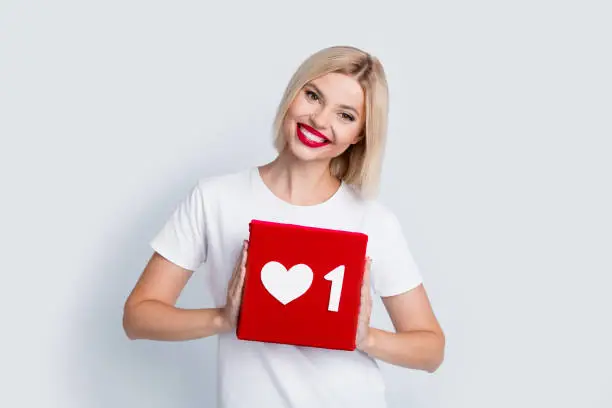 Photo of Photo of toothy beaming woman with bob hairstyle dressed white t-shirt hold social media like box isolated on white color background