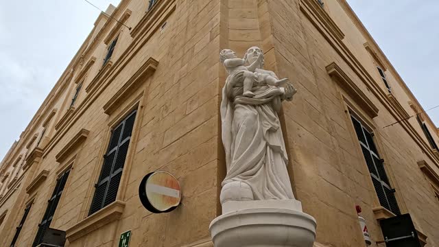 Religious Statue Of A Woman Holding A Child In The Corner Of An Old Building In Valletta