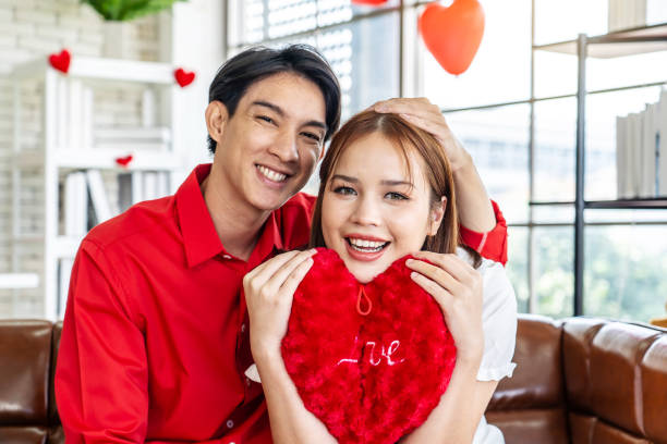 istock Happy couple posing joyfully with heart-shaped cushions in their hands 1922146564
