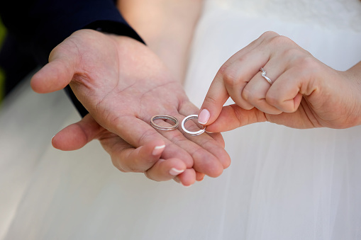The hands of the bride and groom are holding wedding rings. A wedding or engagement.