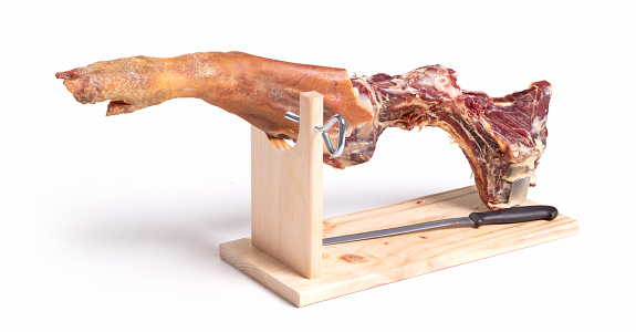 Leg of spanish jamon serrano, dry cured ham, on a white background, half eaten