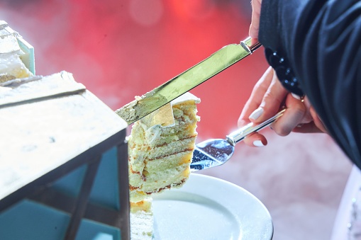 A piece of birthday cake in your hands. Cutting the dessert. A wedding or a birthday.
