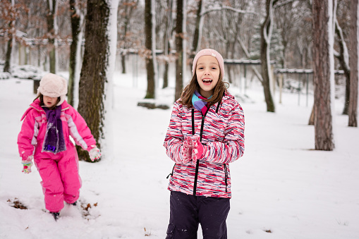 Happy two girls enjoying the snow during a winter day in the park.