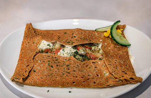 French specialty, buckwheat crepe with frog legs, tomatoes and cheese at a winstub restaurant in Colmar, France, Alsatian Wine Route village