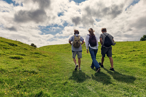 Three teenage kids are hiking in the Cotswolds, Worcestershire, United Kingdom. They are walking on the green hills.
Sunny summer day.
Shot with Canon R5