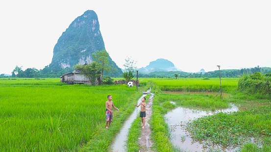 Two children enjoying with football in green mountain background in a countryside Laos.