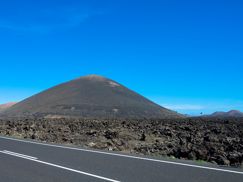 Panoramic view of empty asphalt road LZ-67 in volcanic landscape of Timanfaya National Park, Lanzarote, Canary Islands, Spain, Europe