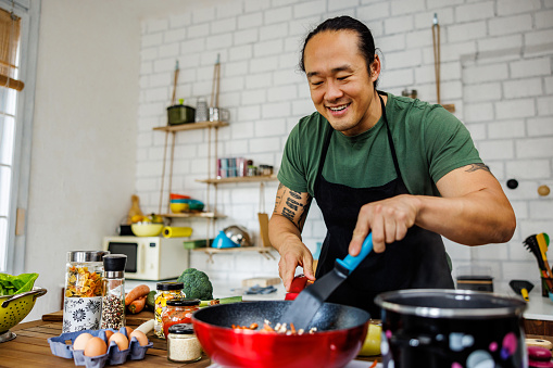 Satisfied man frying vegetables