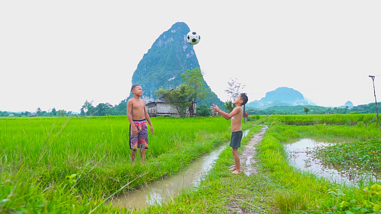 Two children enjoying with football in green mountain background in a countryside Laos.