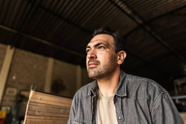 Contemplative farmer looking away at a warehouse