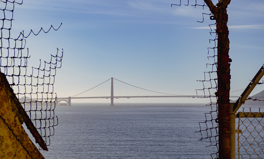 The view of Golden Gate Bridge through a broken chain link fence