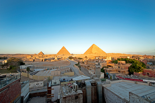 Full profile of Great Sphinx including pyramids of Menkaure and Khafre in the background on a clear sunny, blue sky day in Giza, Cairo, Egypt with no people