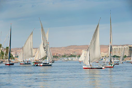 Aswan, Egypt - Decemebr 14 2023: Navigating the Nile River, several tour boats waiting for tourists near a Nubian town.