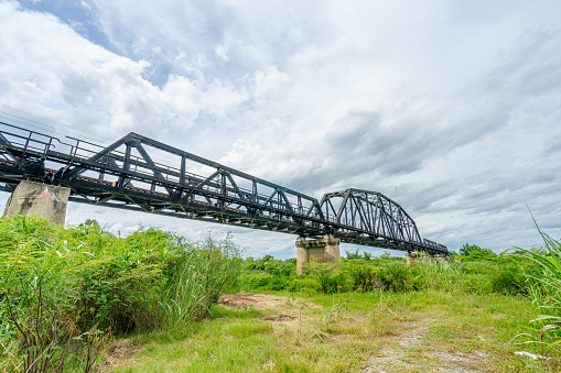 Beautiful scenic of black steel railway bridge across the river (Pasak river) in Lop Buri, Thailand.