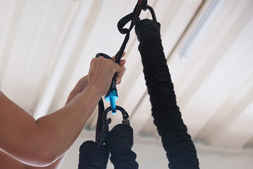 Close-up shot of Unrecognizable hand preparing a bungee cord and harness for indoor workout