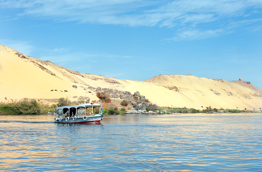 Tourist tour boat, The Cataracts, Aswan, River Nile, Egypt. The Cataracts of the Nile are the rock and islet strewn shallow waters of the upper river that hinder navigation. The River Nile has always and continues to be a lifeline for Egypt. Trade, communication, agriculture, water and now tourism provide the essential ingredients of life - from the Upper Nile and its cataracts, along its fertile banks to the Lower Nile and Delta. In many ways life has not changed for centuries, with transport often relying on the camel by land and felucca on the river