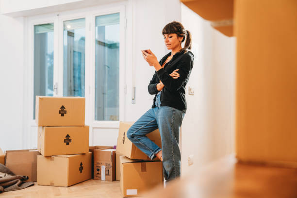 istock A woman is using her mobile phone while is resting during the home move 1922335076