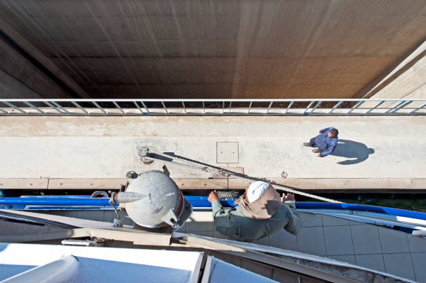 Crewman directs shoreman, Esna locks, Esna, River Nile, Egypt. Originally constructed during the Ptolemaic era to control the flow of the Nile, it preserves and stores water for agriculture and improves navigation, Esna Lock and weir barrage connect the upper and lower parts of the river and are essential for transportation of passengers in river cruise ships and for freightThe River Nile has always and continues to be a lifeline for Egypt. Trade, communication, agriculture, water and now tourism provide the essential ingredients of life - from the Upper Nile and its cataracts, along its fertile banks to the Lower Nile and Delta. In many ways life has not changed for centuries, with transport often relying on the camel on land and felucca on the river