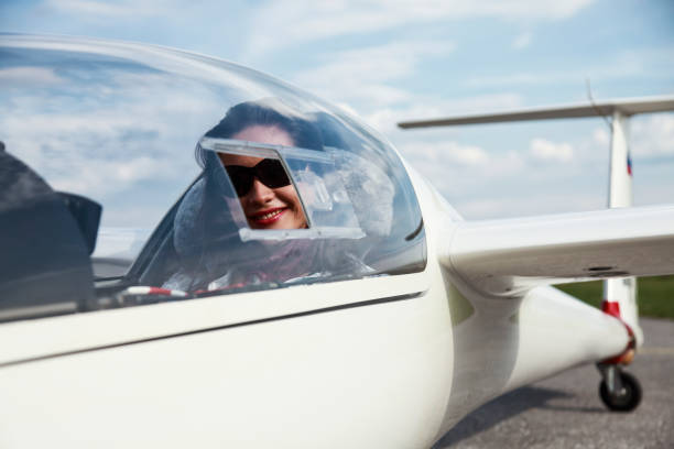 Woman sitting in a glider plane on a small airport. Happy and smiling. Ready to take off.