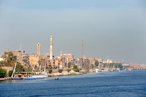 Esna city waterfront, Esna, River Nile, Egypt. The River Nile has always and continues to be a lifeline for Egypt. Trade, communication, agriculture, water and now tourism provide the essential ingredients of life - from the Upper Nile and its cataracts, along its fertile banks to the Lower Nile and Delta. In many ways life has not changed for centuries, with transport often relying on the camel on land and felucca on the river