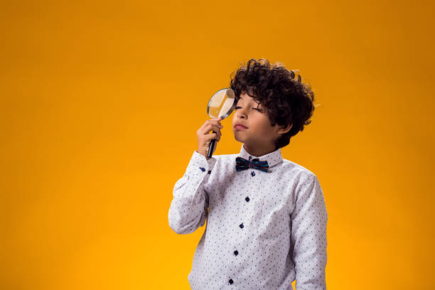 istock Child boy looking through magnifier over yellow background. Education and curiosity concept 1922366170