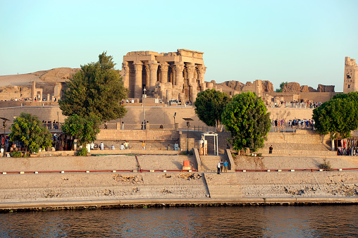 Double temple of Kom Ombo, Aswan governate, River Nile, Egypt. The Temple of Kom Ombo is a double temple in Kom Ombo, Aswan Governorate, Upper Egypt, constructed during the Ptolemaic dynasty dedicated to Sobek and Horus. The River Nile has always and continues to be a lifeline for Egypt. Trade, communication, agriculture, water and now tourism provide the essential ingredients of life - from the Upper Nile and its cataracts, along its fertile banks to the Lower Nile and Delta. In many ways life has not changed for centuries, with transport often relying on the camel on land and felucca on the river