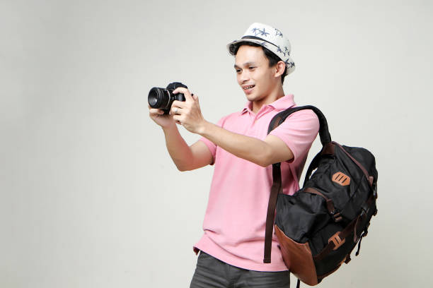 young man with a camera in hand and in a plaid t-shirt on a gray background indoors photographer. High quality photo