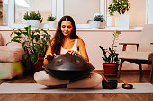 Beautiful young woman playing handpan musical instrument. Sound healing concept.
