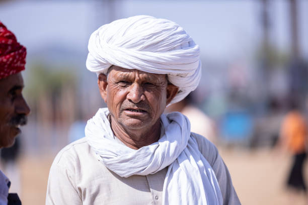 Pushkar, Rajasthan, India - November 2022: Pushkar fair, Portrait of an rajasthani old male with in white traditional dress and colorful turban at pushkar fair ground.