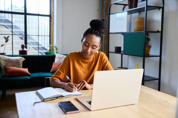istock Young businesswoman writing notes while working on a laptop in her office 1922401071