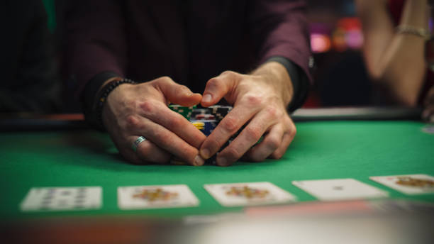 istock Anonymous Man Dressed in Suit Collecting his Prize of Poker Chips in a Modern Casino. Lucky Male Winner Hitting the Jackpot, Happy About His Risky Bet that Paid of Handsomely 1922401607