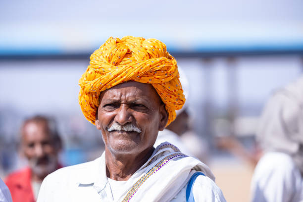 Pushkar, Rajasthan, India - November 2022: Pushkar fair, Portrait of an rajasthani old male with in white traditional dress and colorful turban at pushkar fair ground.