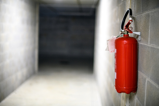 Urban details in Italian town: Fire extinguisher in underground parking lot garage