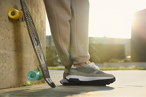 Man with skateboard wearing stylish sneakers outdoors, closeup