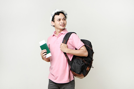 Asian man backpacker holding passport. digital nomad and travelling concept. on isolated background