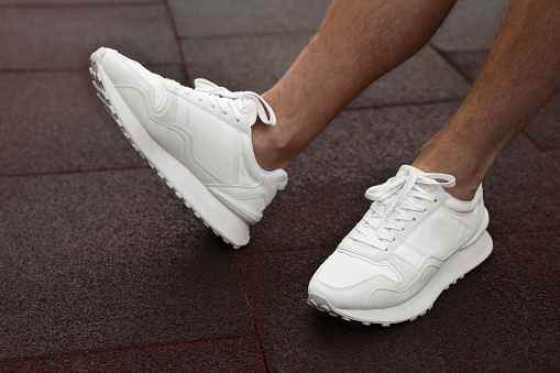 Man wearing pair of stylish sneakers outdoors, closeup