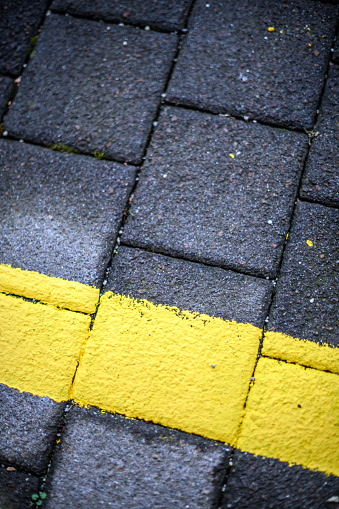 Urban details in Italian town: Yellow line on bricks