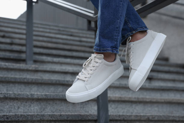 istock Man in stylish sneakers sitting on railing outdoors, closeup. Space for text 1922439528