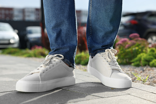 Man wearing pair of stylish sneakers outdoors, closeup